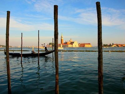 A gondolier navigates the Venetian Lagoon, a shallow, 210-square-mile bay fed by the Adriatic Sea, at sunset.