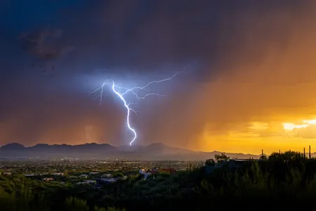 Lightning from a summer monsoonal thunderstorm strikes in Tucson just as the sun sets.&nbsp;