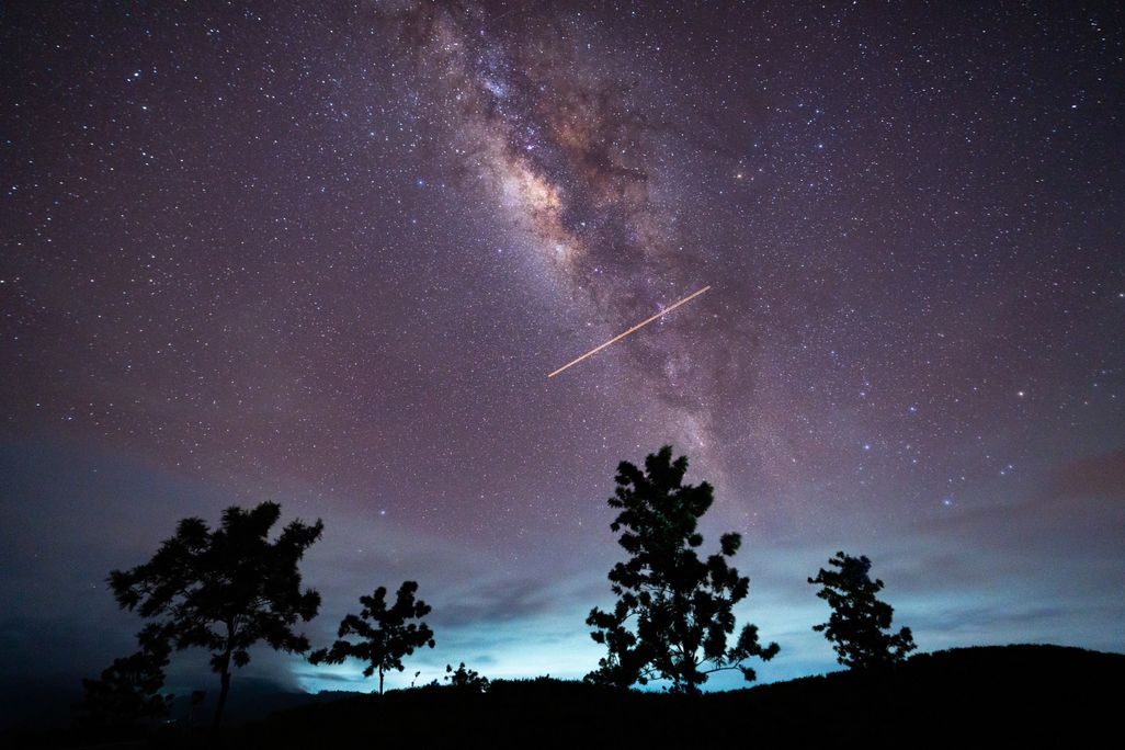 a comet streaks across a purple sky
