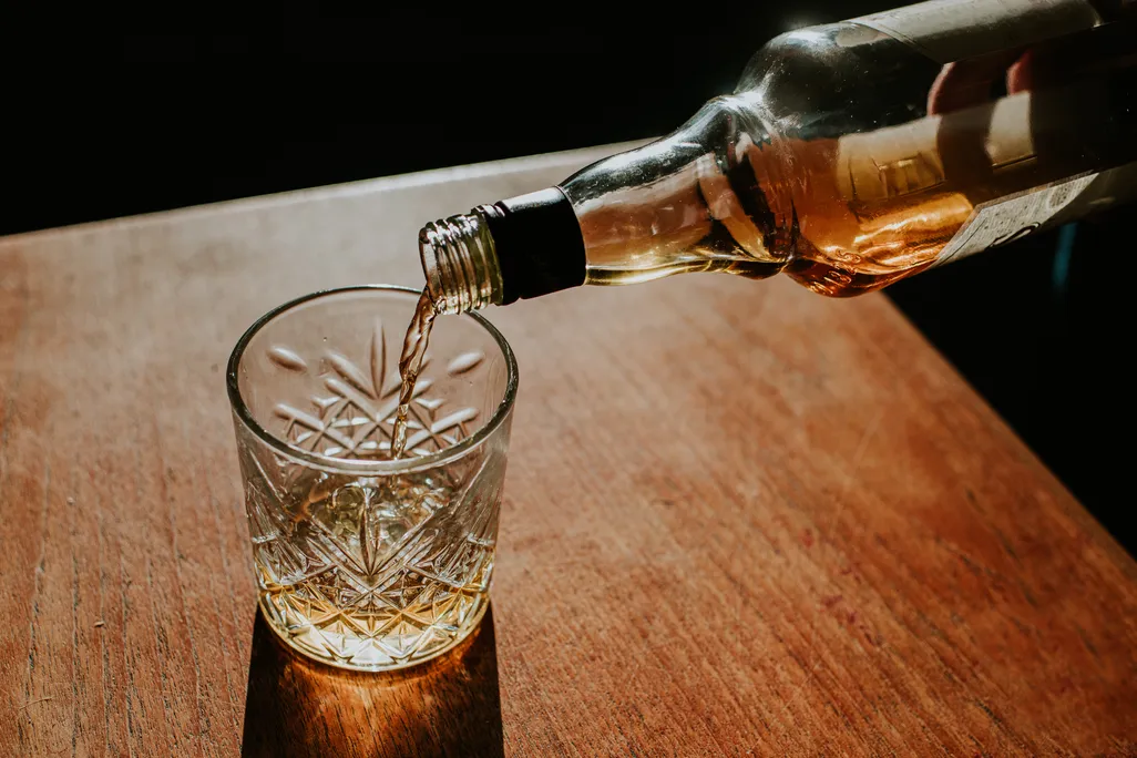 whiskey being poured into a glass on a table