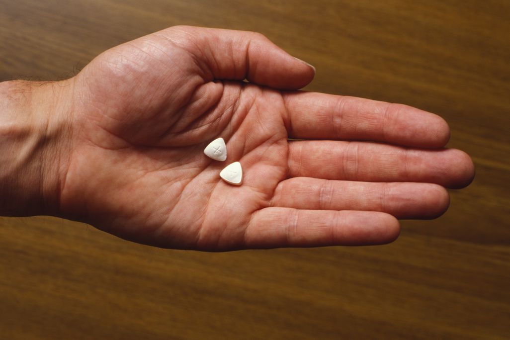 A person's open hand holding two triangle-shaped pills