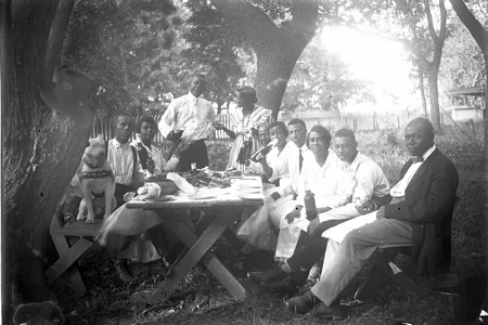 Photograph of ten people and a dog at a picnic table, 1919&ndash;1925