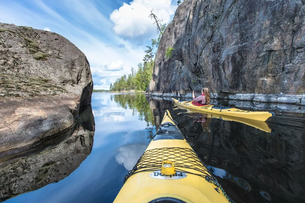 Front of yellow kayak and another kayak with a woman in it on the water