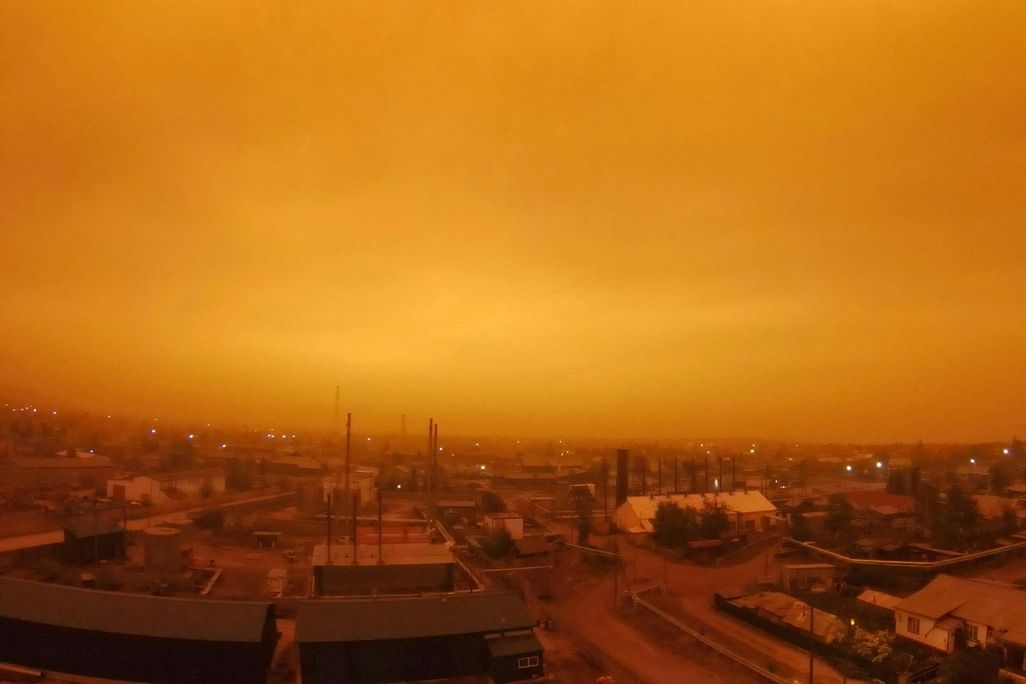 A photo of a small town in Russia. Its skies glowing an eerie amber color as wildfires continue to rage in Yakutia. 