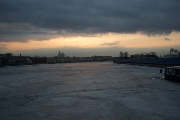 Frozen river in big city at sunset thumbnail