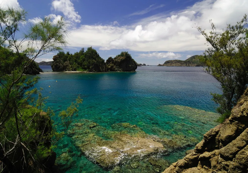A landscape photo of Japan's Bonin Islands. Rock formations jut up from the clear, bright water.