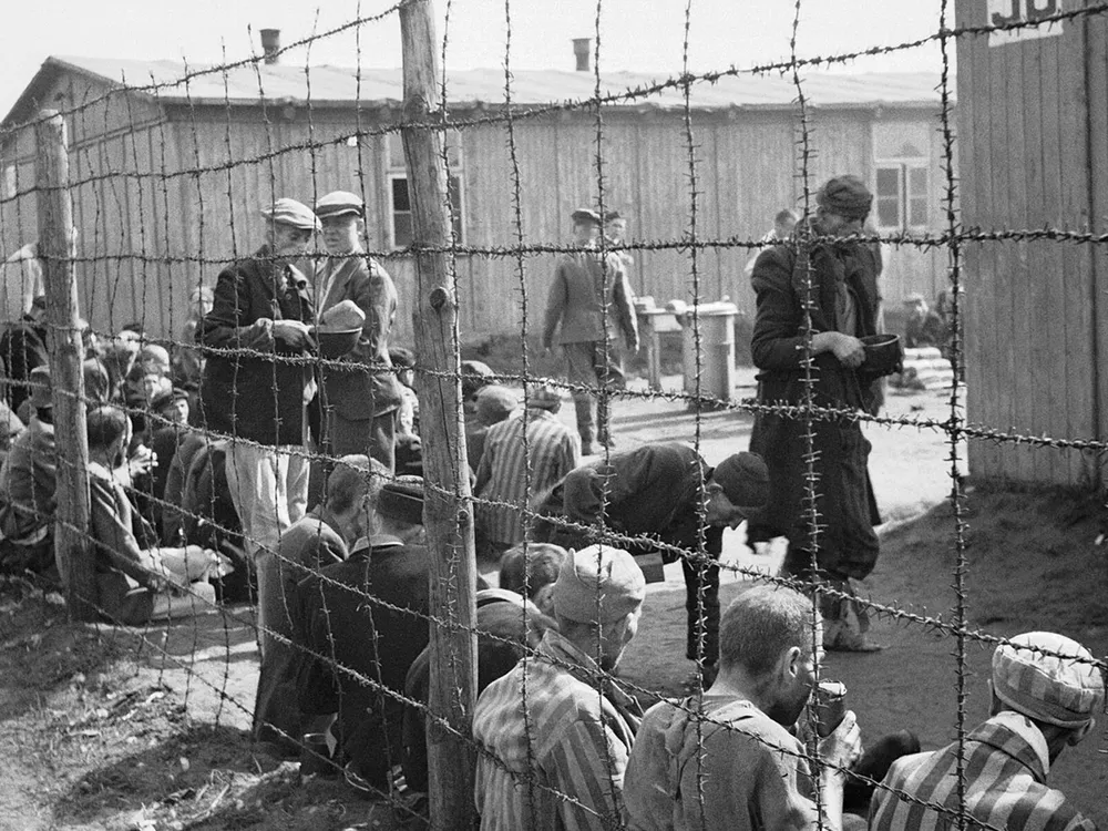 Prisoners sit by a wire fence following the liberation of Bergen-Belsen in April 1945.