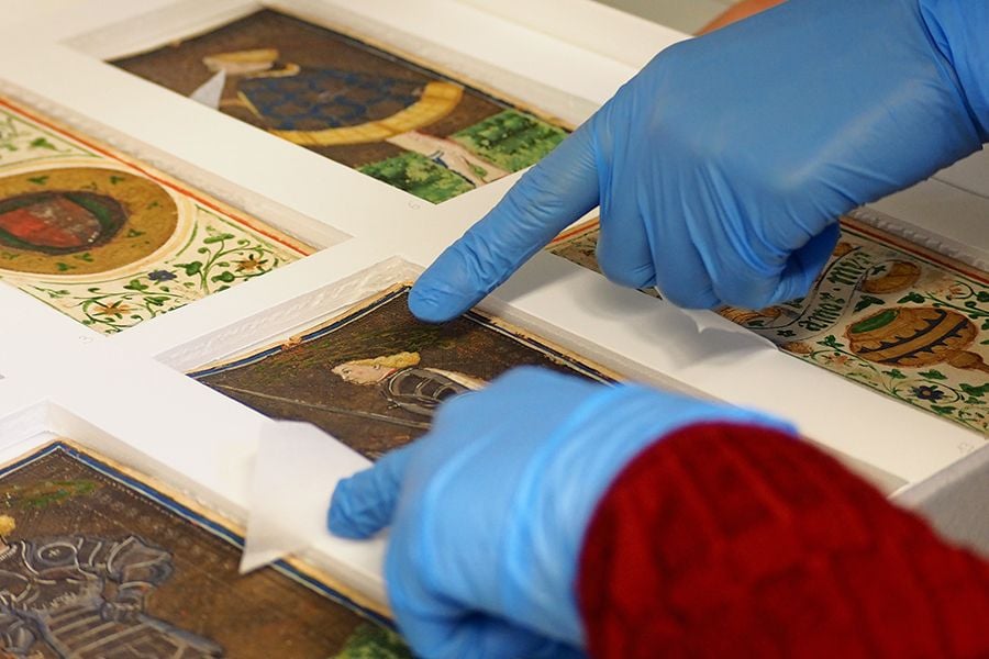 a hand in blue gloves points at tarot cards