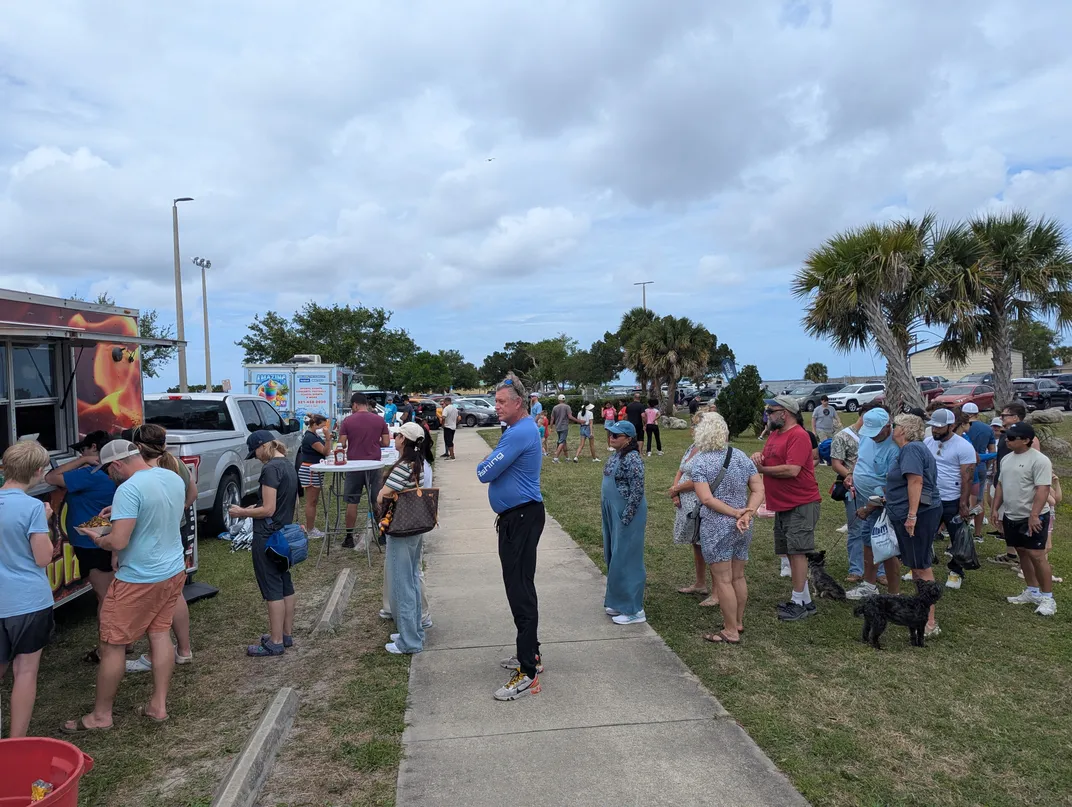 people stand in line at a food truck