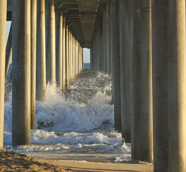 Waves breaking between pier pylons thumbnail
