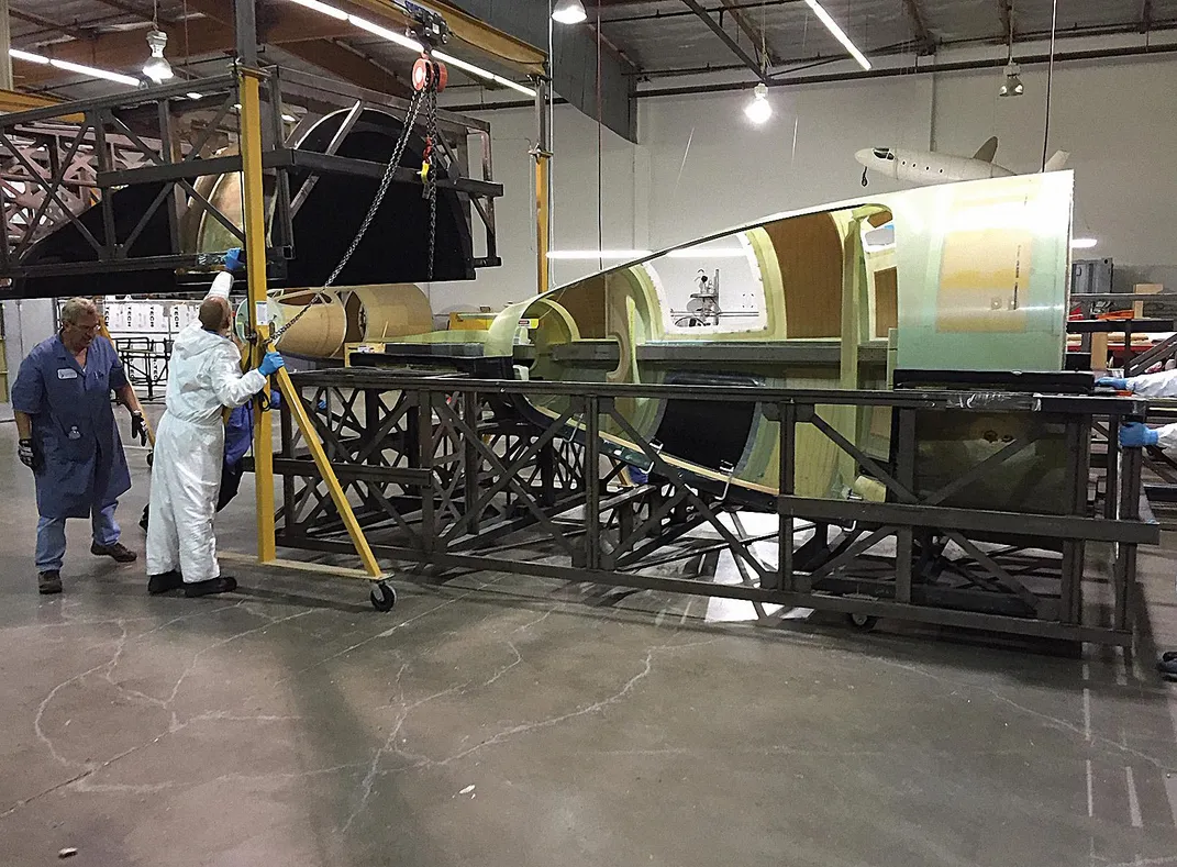 people removing fuselage from a mold