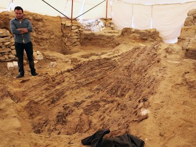 An archeologist surveys the in-progress excavation of an approximately 4,500-year-old boat.