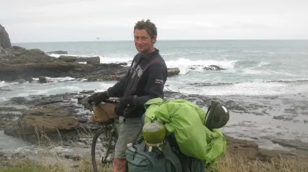 The author facing off with the edge of the world, where the gray and blustery waters of the Southern Ocean meet the rocks of Curio Bay, in the Catlins.