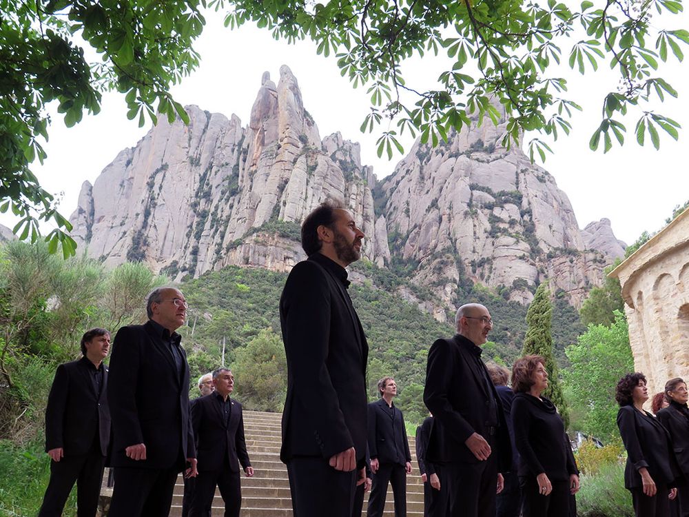 Several men and women dressed in all black, standing in formation with a towering stone mountain behind them.