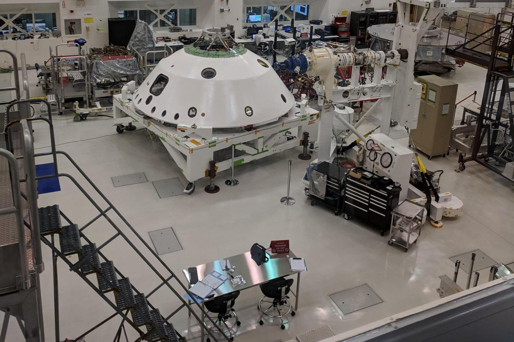 A NASA clean room containing lots of equipment is captured from an elevated point of view.
