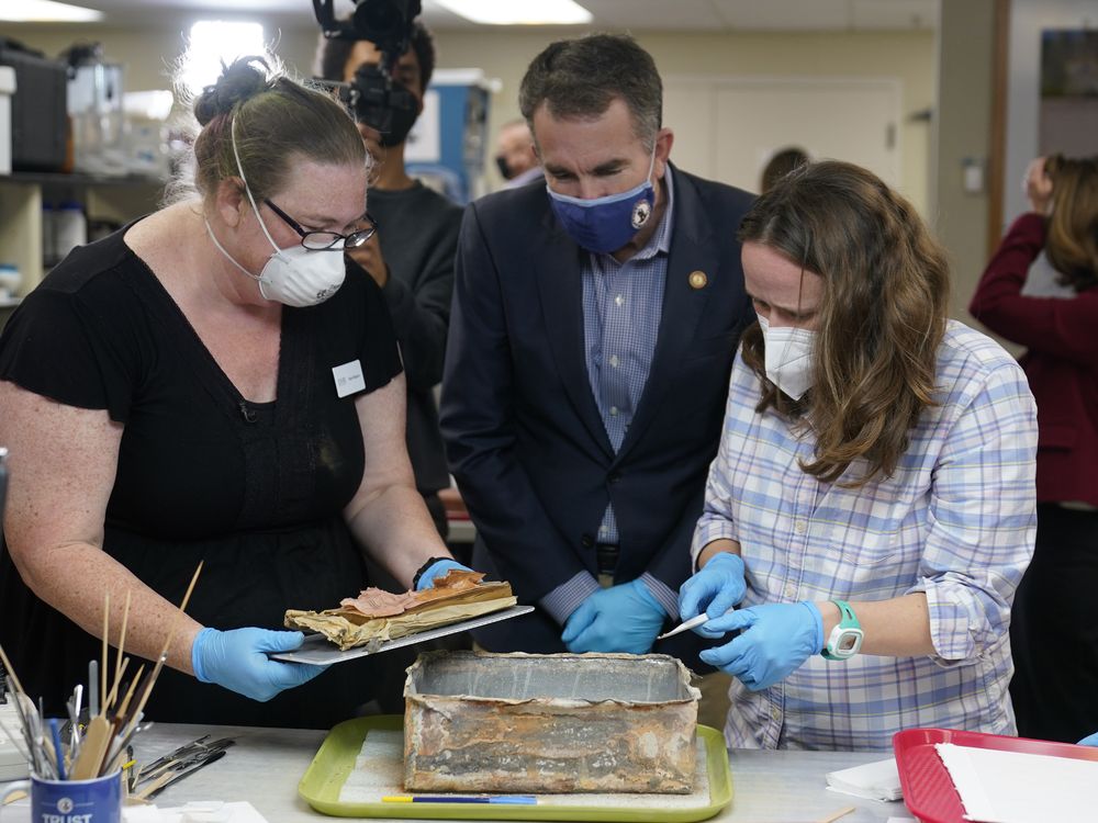 Governor Ralph Northam watches conservators remove the contents of the time capsule
