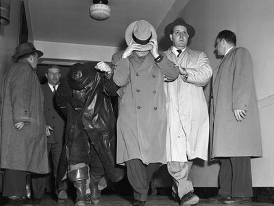 MAFBI agents (right) escort Vincent James Costa (center) and Michael Vincent Geegan (left) from Federal Court 1/12. The two men together with four others were arrainged before UC commissioner for the $1,219,000 Brinks robbery on January 17,1950.