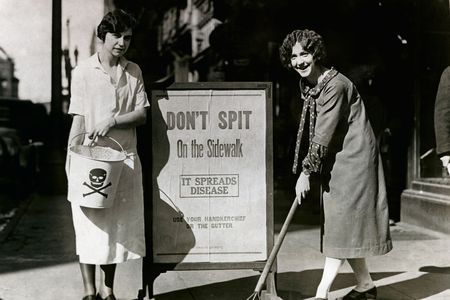 Allene Goodenough (right) and Helyn James of the Young Women's Christian Association mop up a spot on the sidewalk where someone expectorated by an anti-spitting sign during a public health campaign in Syracuse, New York, in 1900. 
