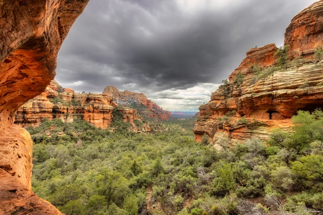 Clouds, trees and rust-colored mountains
