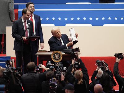 President Donald Trump holds up an executive order. He signed dozens of executive orders on his first day in office, undoing many of his predecessor&rsquo;s policies.