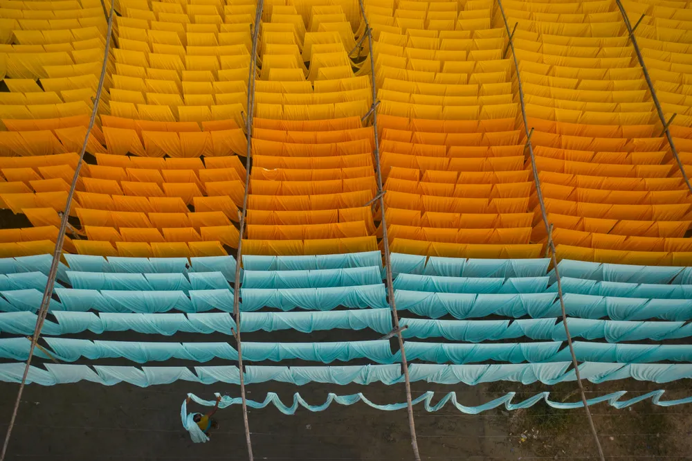 Thousands of meters of cloth drying in the sunlight after the dying process. These colored cloths make T-shirts.