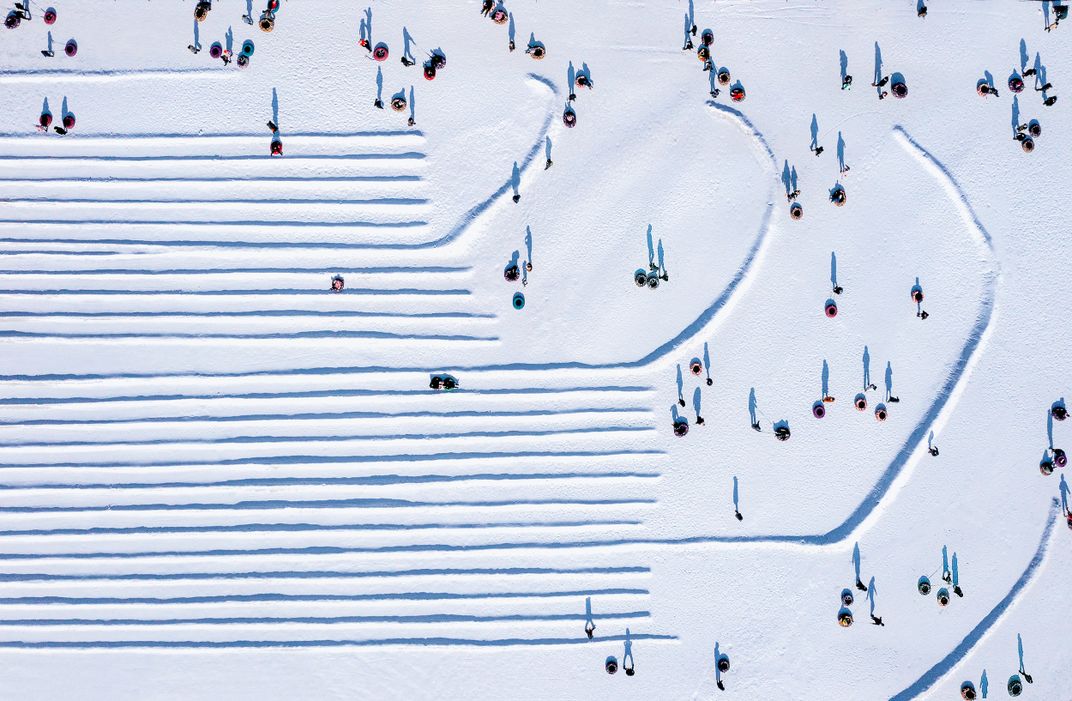6 - People’s shadows dot the landscape as snow tubers wait for their chance for a thrilling and frigid ride.