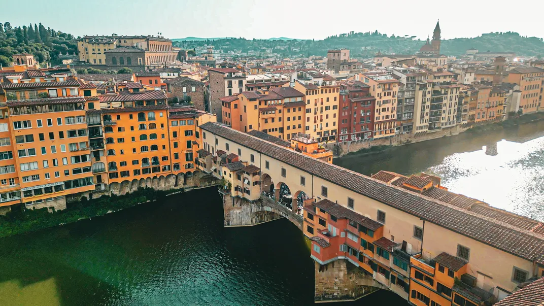 The historic Ponte Vecchio, spanning the Arno River, with the Pitti Palace in background