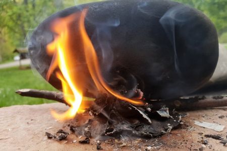 Burning birch bark to produce sticky tar.
