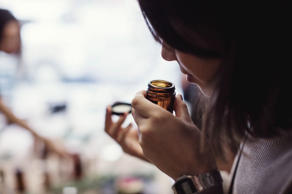 Woman smells open bottle close to her nose