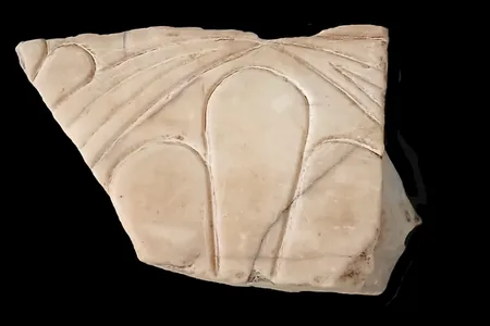 The marble fragment is decorated with part of a lotus flower pattern.