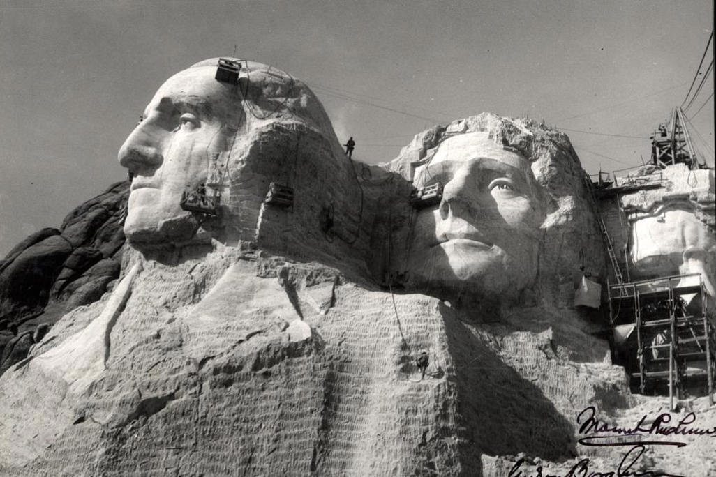 A close up view of workers carving the heads of George Washington and Thomas Jefferson on Mount Rushmore