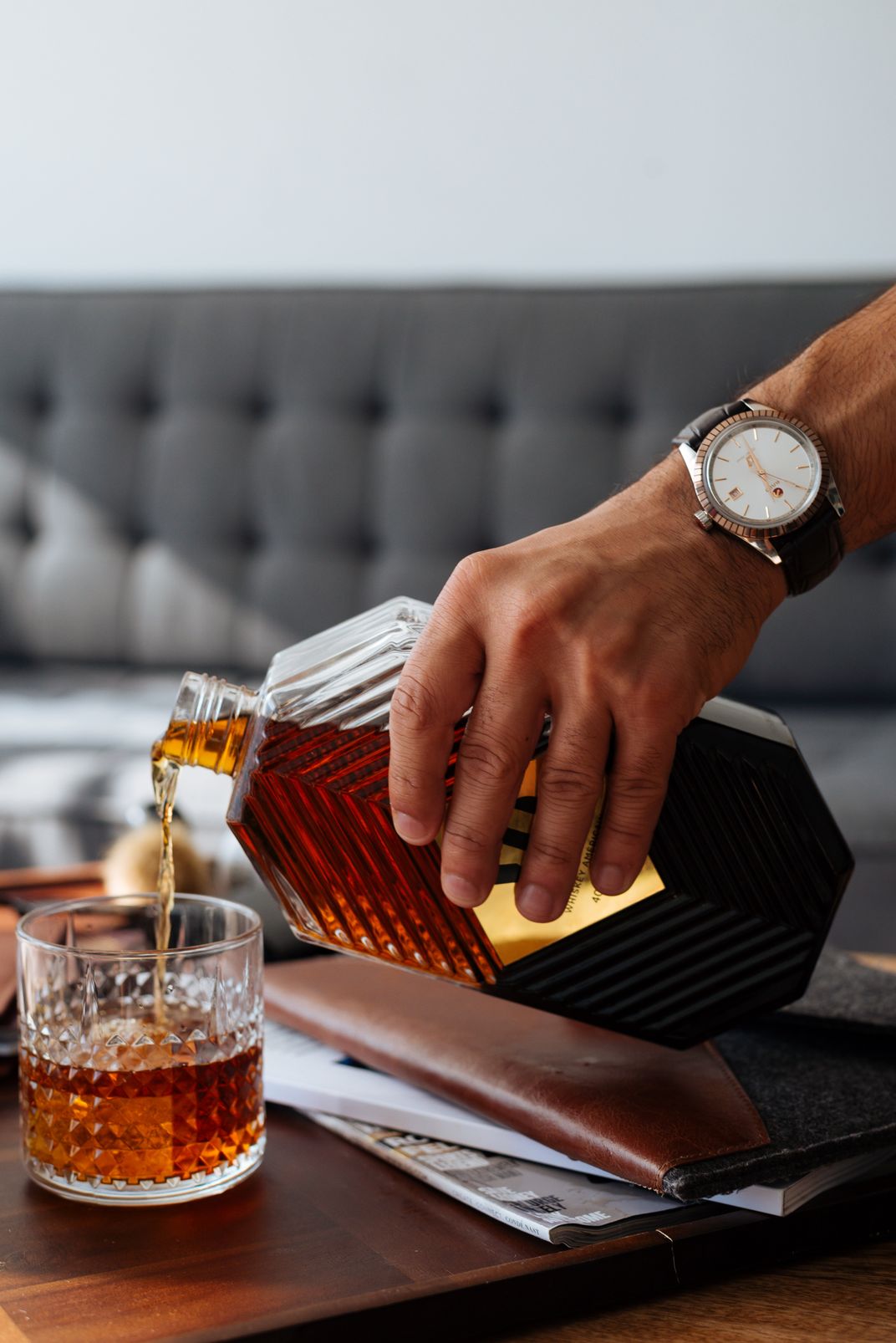 Hand pouring a glass of whiskey from a bottle