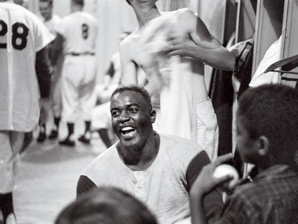 Jackie Robinson smiling in a locker room