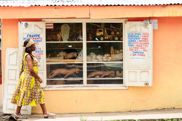 A lady passing by a handicraft shop at Libreville, Gabon. Handicrafts made in Gabon are usual things to buy for tourists coming at Gabon. thumbnail