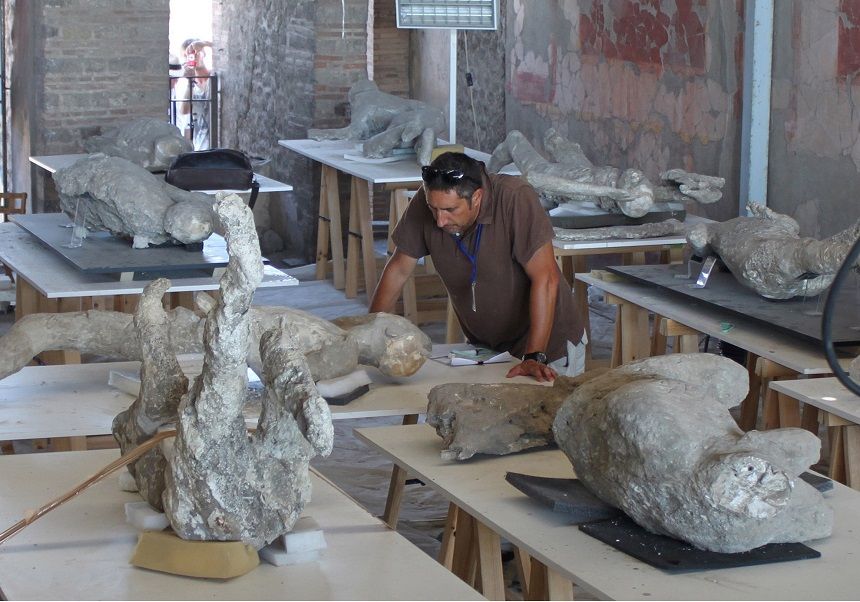 A man standing near plaster casts of human bodies