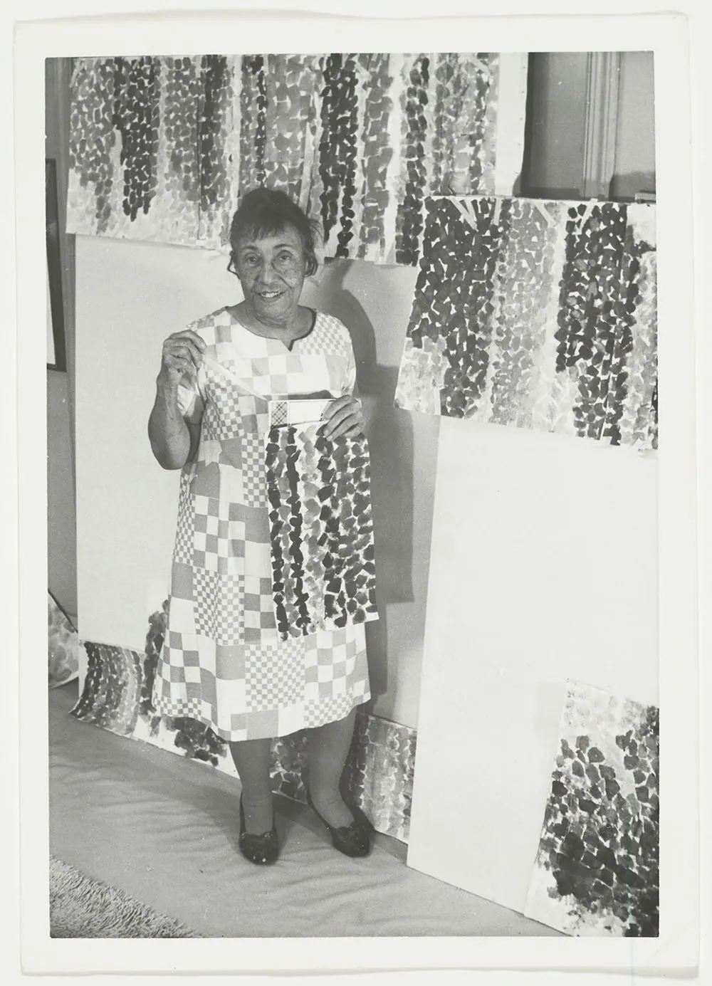 Photograph of Alma Thomas showing off Alma's Stripes in her studio
