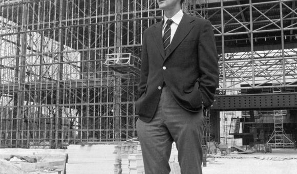 Michael Collins, the Museum's third director, stands before the steel skeleton of the new National Air and Space Museum in July 1974.