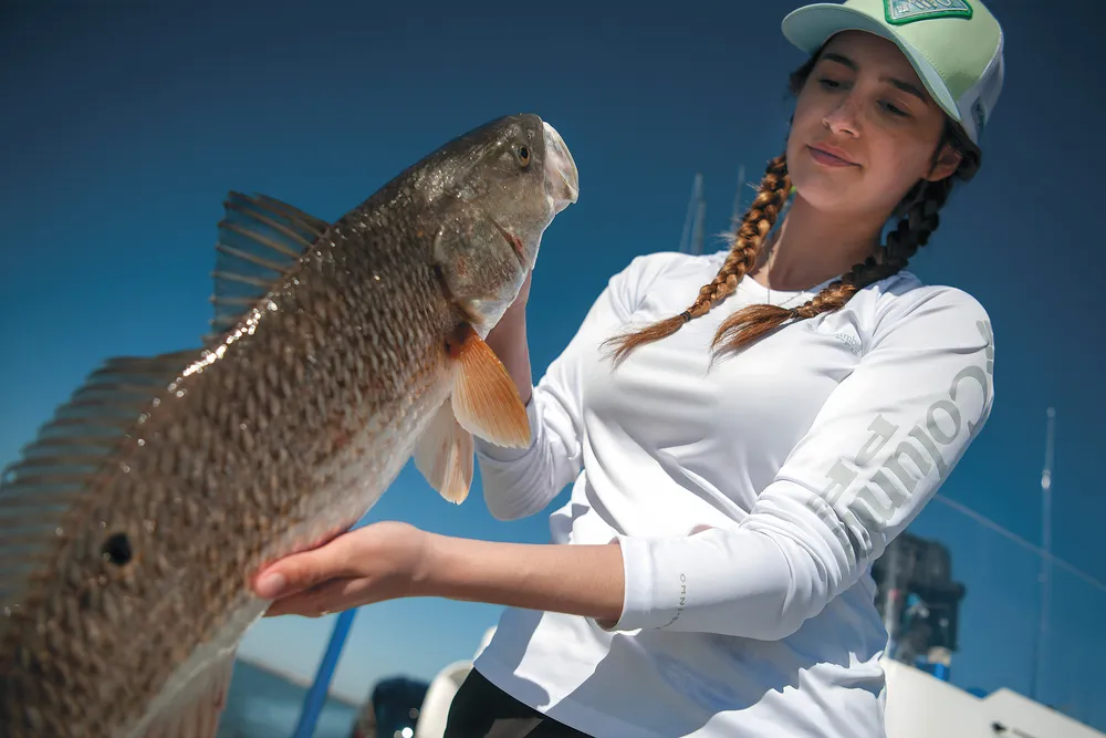 a women holds a freshly caught fish