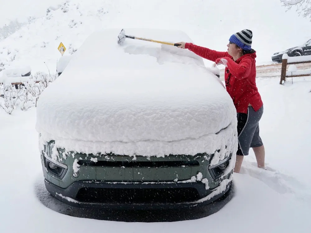 A person clears off their car of snow