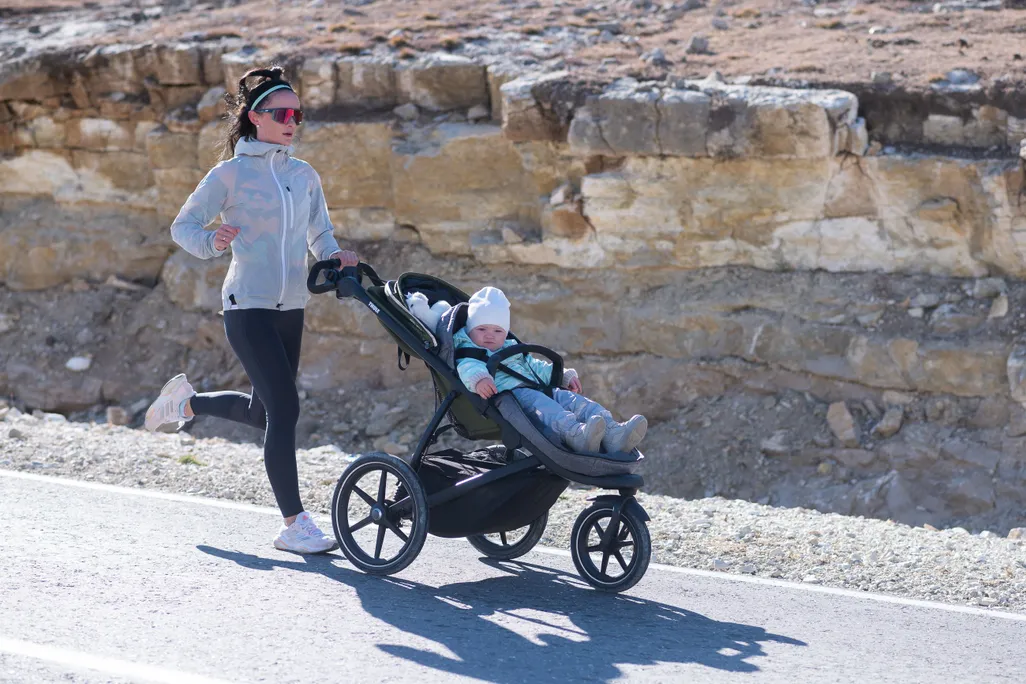 A woman jogging while pushing a stroller