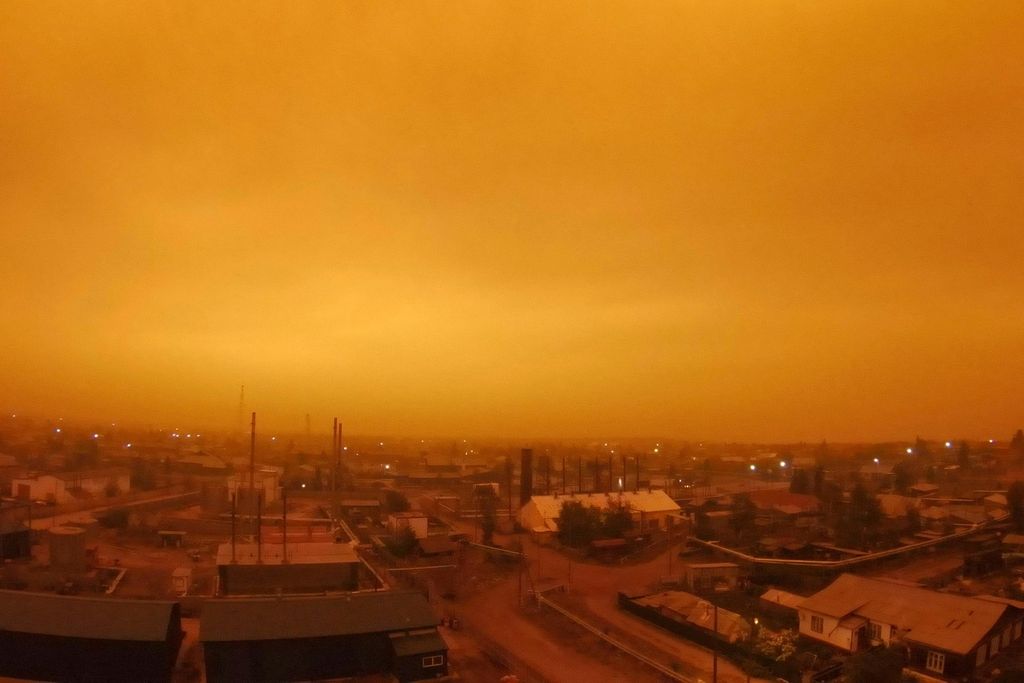 A photo of a small town in Russia. Its skies glowing an eerie amber color as wildfires continue to rage in Yakutia.