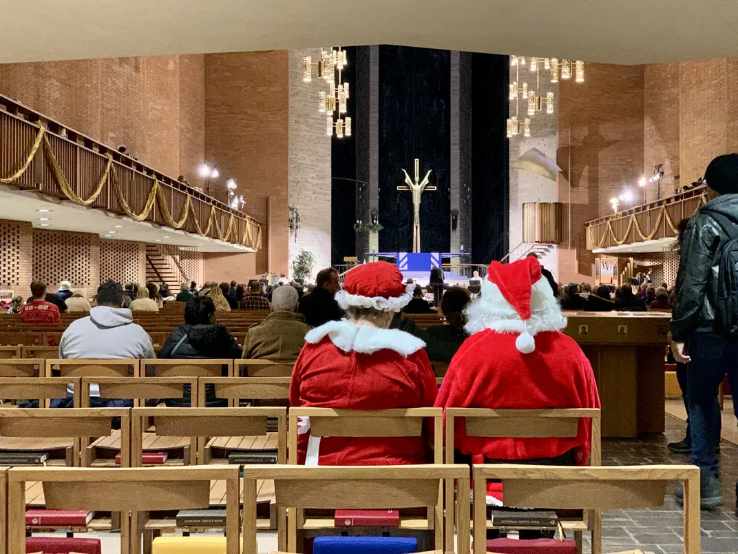 Santa and Mrs. Claus sit in the back of a church