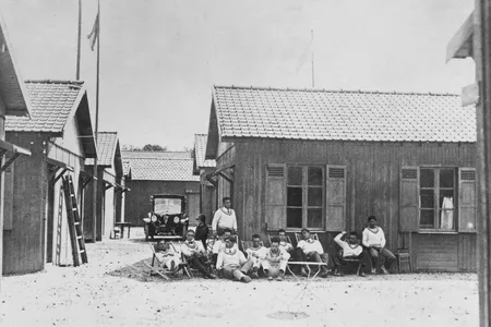 Athletes sit in front of a cabin in the Olympic Village at the 1924 Summer Olympics in Paris, France