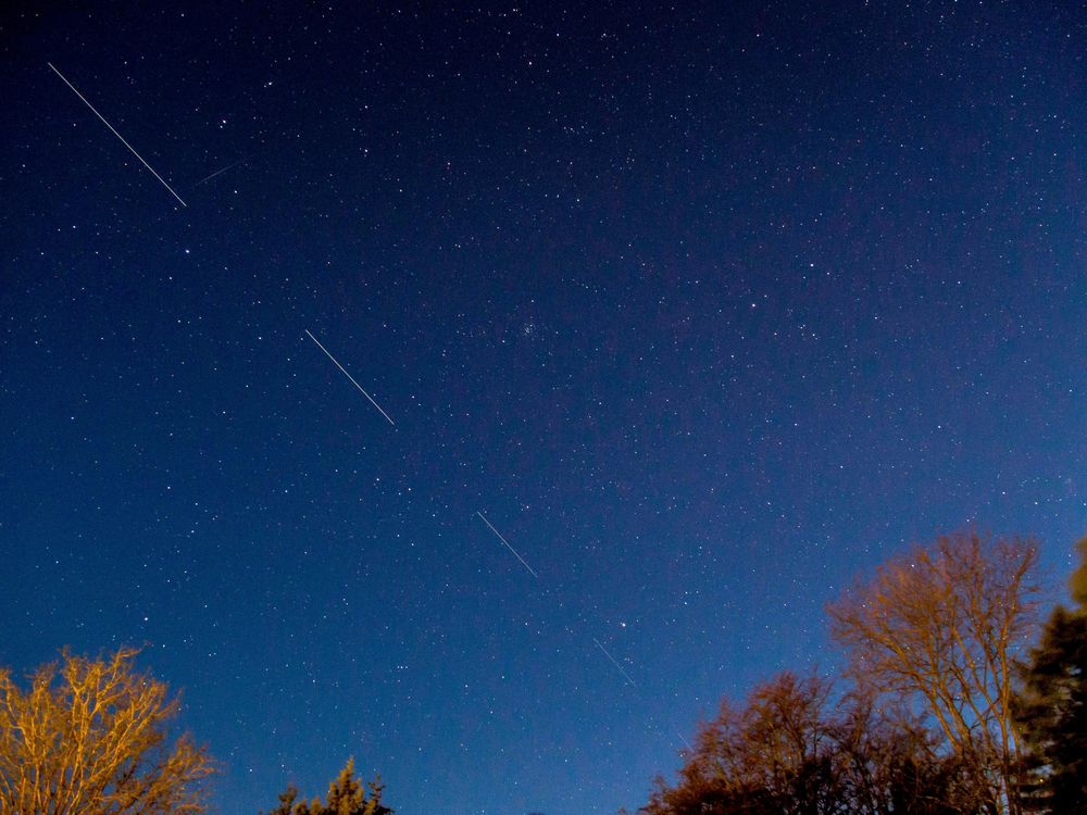 A dark blue night sky, with pinpricks of stars and long streaks where the satellite traveled through the shot