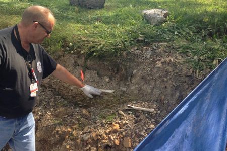 Schuylkill County Deputy Coroner Joe Pothering points to human bones in embankment along Route 61 in Schuylkill Haven, Pennsylvania August 14, 2015. Forensic archaeologists on Friday began excavating a highway embankment in eastern Pennsylvania, looking for more bones believed to be from impoverished victims of the worldwide Spanish flu pandemic in 1918.