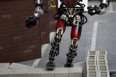 Team WPI-CMU’s robot climbs over cinder blocks during the finals of the DARPA Robotic Challenge