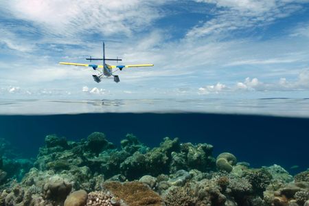 A Twin Otter seaplane flying over the shallow waters of the Maldives. 