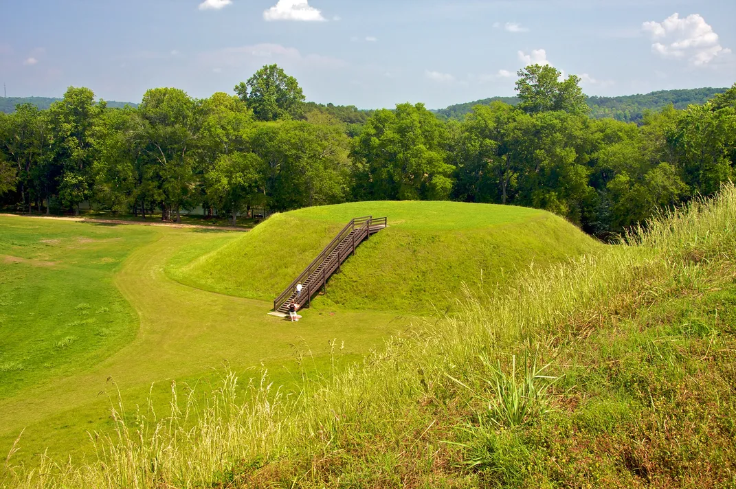 an elevated mound in the grass with a flat top and stairs leading up to it