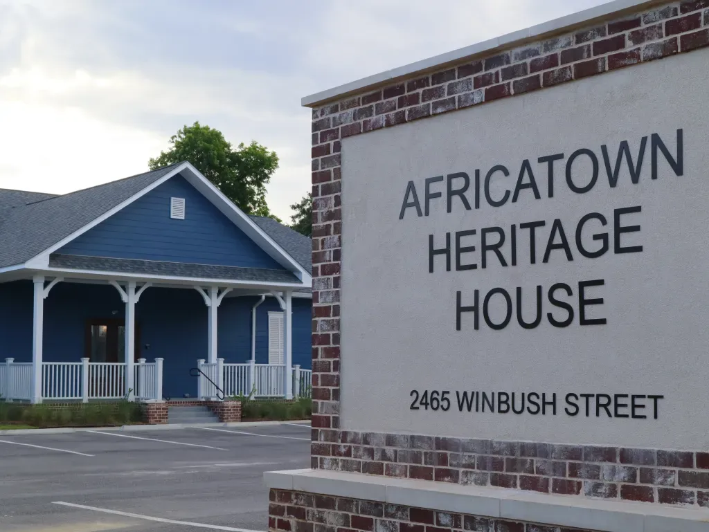 Sign that says Africatown Heritage House in front of blue building