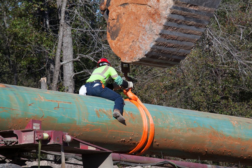 A worker unloads pipe from a truck during construction of the southern portion of the Keystone XL pipeline.
